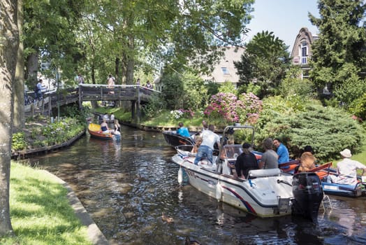 GIETHOORN, NETHERLANDS - JULY 18, 2015: Unknown tourists on boating trip in a canal in Giethoorn on july 18 2015. The beautiful houses and gardening city is know as "Venice of the North"