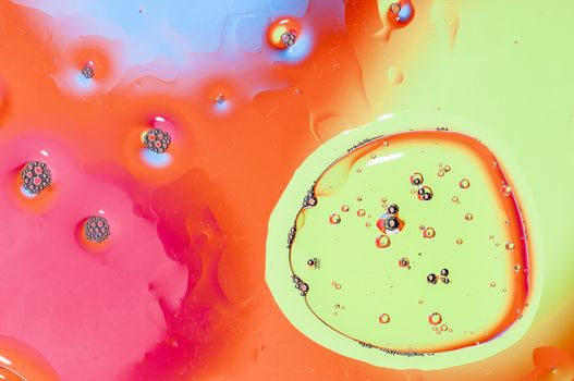 Oil drops on water surface lit from beneath.