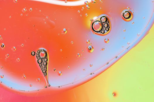 Oil drops on water surface lit from beneath.