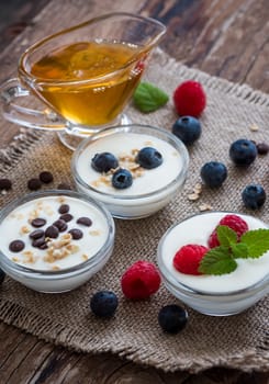 Three Little Bowls Full of Healthy Yogurt with Fruit or Chocolate and Honey on Wooden Rustic Table