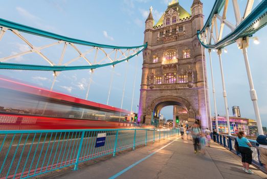 Double Decker bus crossing Tower Bridge at dusk.