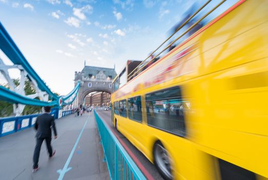 Blurred image of yellow bus fast moving along Tower Bridge.