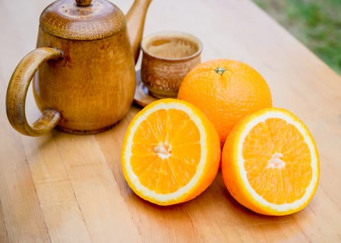 Slice of orange and wooden vase on wooden table.