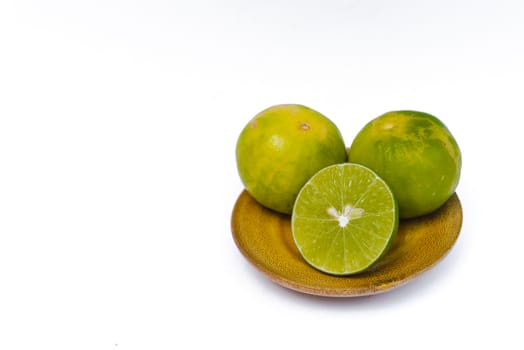 Lime placed in wooden tray on white background.