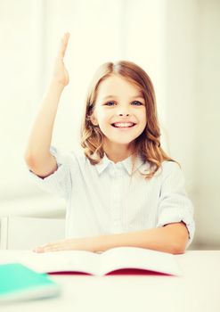 education and school concept - little student girl studying and raising hand at school