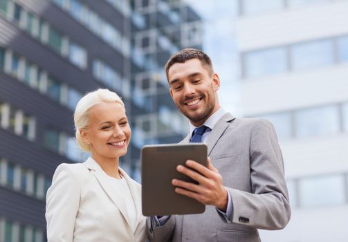 business, partnership, technology and people concept - smiling businessman and businesswoman with tablet pc computer over office building