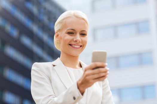 business, technology and people concept - smiling businesswoman with smartphone over office building