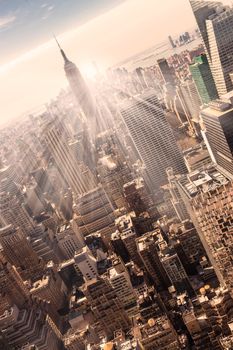 New York City. Manhattan downtown skyline with illuminated Empire State Building and skyscrapers at sunset. Vertical composition. Warm evening colors. 