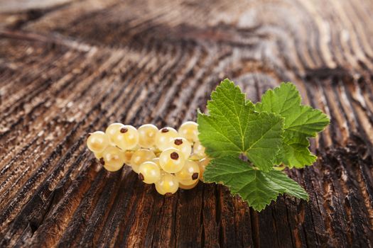 Ripe white currant on old vintage wooden background. Healthy summer fruit eating. 