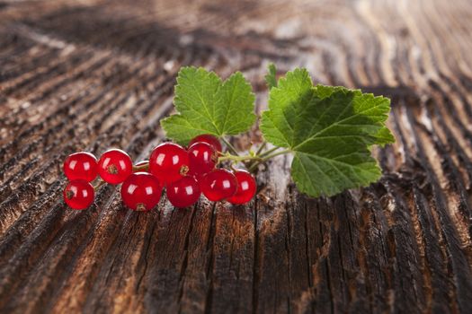 Ripe red currant on old vintage wooden background. Healthy summer fruit eating. 