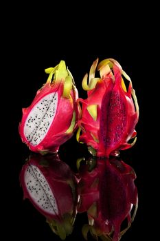Red and white dragon fruits isolated on black background. Pitaya, tropical fruits, minimal luxurious style.