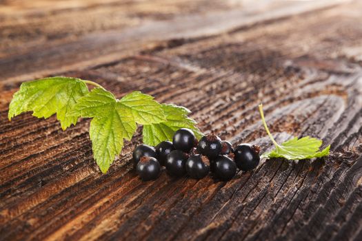 Ripe black currant on old vintage wooden background. Healthy summer fruit eating. 