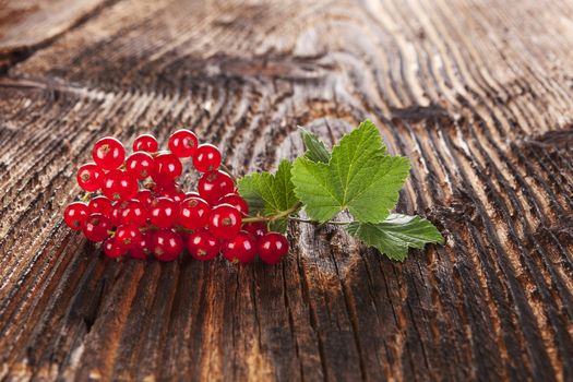 Ripe red currant on old vintage wooden background. Healthy summer fruit eating. 