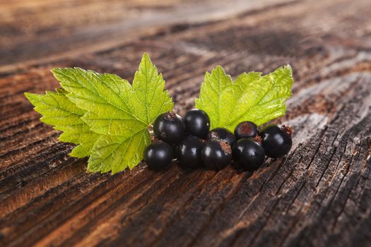 Ripe black currant on old vintage wooden background. Healthy summer fruit eating. 