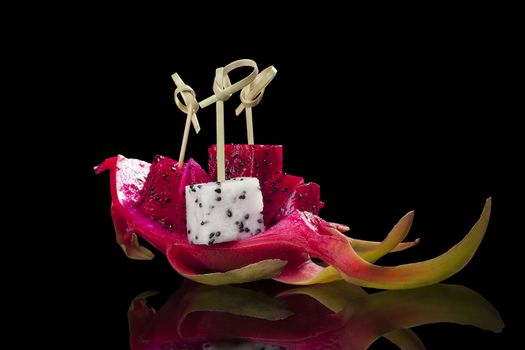 Red and white dragon fruit isolated on black background. Healthy tropical fruit eating. 