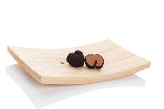 Truffles, rare mushrooms. Cut truffles on wooden plate isolated on white background. Luxurious culinary cooking ingredienets. 