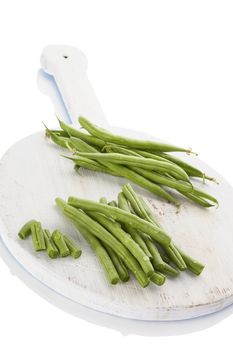 Fresh green beans with water drops on wooden chopping board isolated on white background. Healthy eating. 