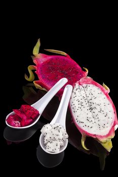 Dragon fruit pieces on spoon isolated on black background. Tropical fruit salad.