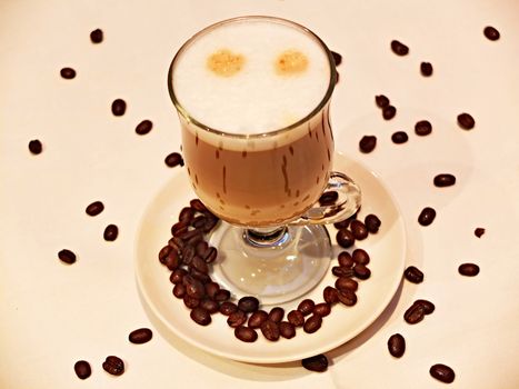 Glass of latte macchiato with coffee beans around
