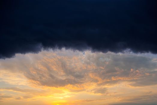 Huge rain cloud lit orange sunset