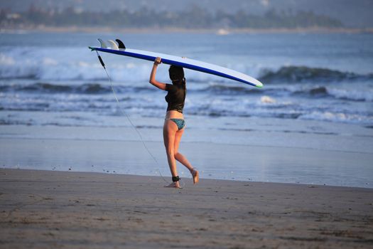 Woman-surfer with board on a coastline. Bali. Indonesia