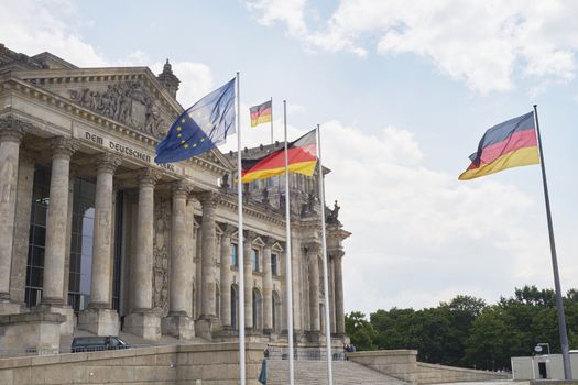 BERLIN, GERMANY - JULY 08: German and EU flags blowing in the wind in front of the Reichstag building. July 08, 2015 in Berlin.