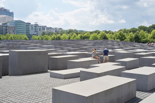 BERLIN, GERMANY - JULY 08: Young couple seated on stone block at the Memorial to the Murdered Jews of Europe. July 08, 2015 in Berlin.