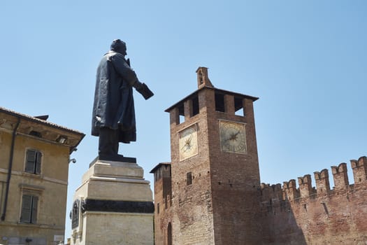 Statue of Cavour with Castelvecchio clocktower in the background, in Verona, Italy.