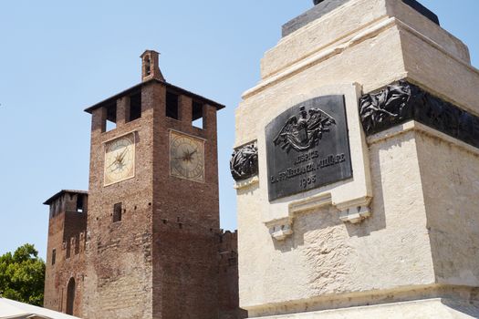 Detail of statue of Cavour with Castelvecchio clocktower in the background, in Verona, Italy.