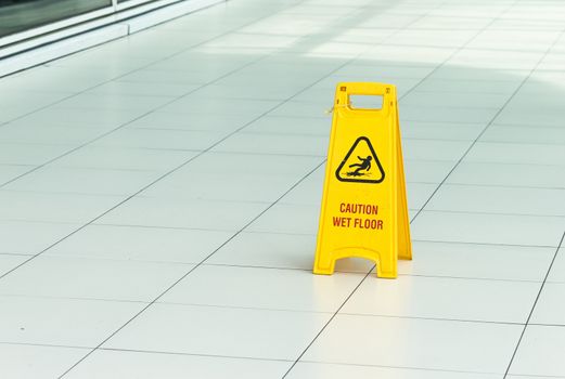 Yellow sign that alerts for wet floor in airport.