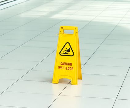 Yellow sign that alerts for wet floor in airport.