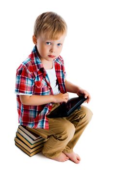 Little boy with a tablet computer sitting on the books on a white background