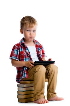 Little boy with a tablet computer sitting on the books on a white background