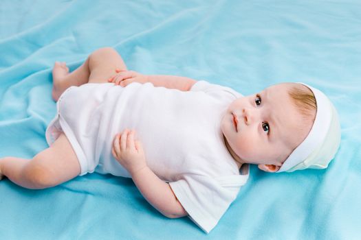 beautiful baby in the cap on a blue blanket