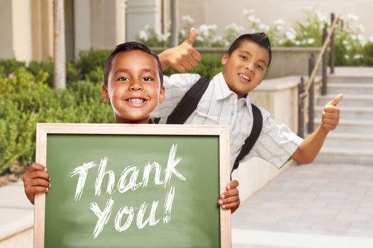 Happy Hispanic Boys Giving Thumbs Up Holding Thank You Chalk Board Outside on School Campus.