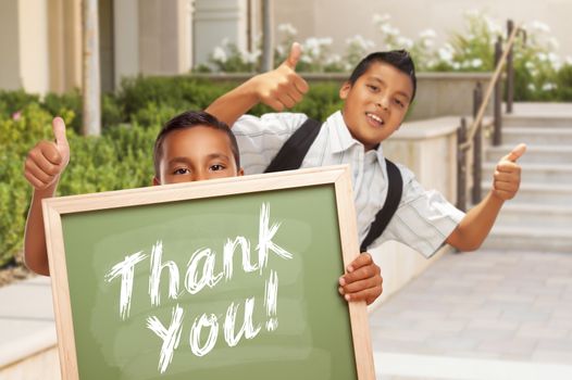Happy Hispanic Boys Giving Thumbs Up Holding Thank You Chalk Board Outside on School Campus.
