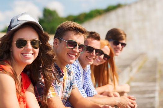 friendship, leisure, summer and people concept - close up of smiling friends sitting on city street