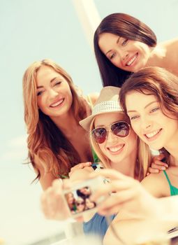 summer holidays and vacation concept - smiling girls taking photo in cafe on the beach