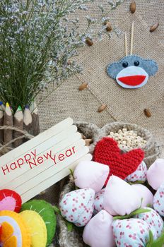 Art idea with funny monkey for happy new year 2016, new year eve time, handmade monkey face, clockwise, colorful  hand made fruit, fibre strawberry, flower decor on burlap background, vintage concept