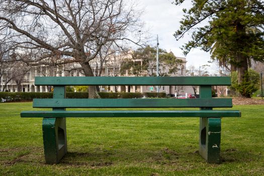 A green park bench in an empty park in Melbourne.