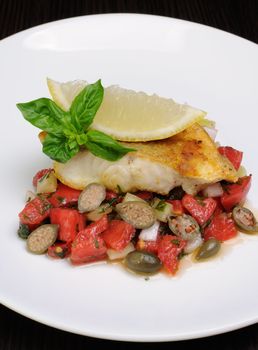 slice of baked fish perch with vegetable garnish and lemon