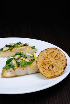 slice of baked fish perch with herbs and lemon slices