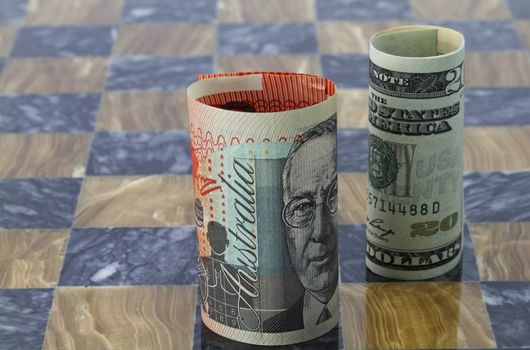 American and Australian money stand on chess board reflect themes of global investment, trade partners, worldwide commerce, and business connections.  Strategies and competition with risk and opportunities are symbolized. 