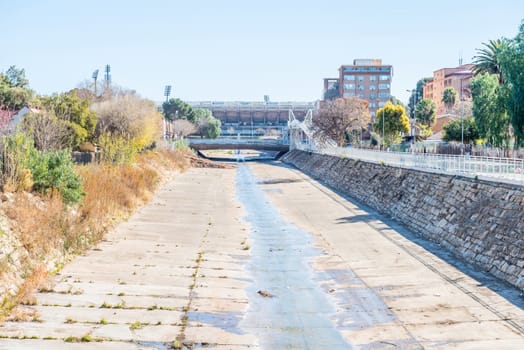 BLOEMFONTEIN, SOUTH AFRICA - JULY 19, 2015: The Bloemspruit, a small river flowing through Bloemfontein. The Free State Rugby Stadium and the athletics stadium, which share facilities are in the back