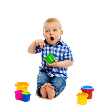 A little boy in a plaid shirt and jeans with toys on a white background