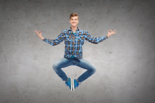 happiness, freedom, movement and people concept - smiling young man jumping in air over concrete wall background
