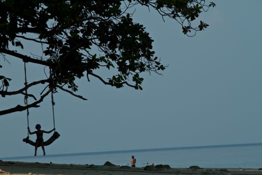 Child on a rudimentary swing at the beach in thailand during the summer