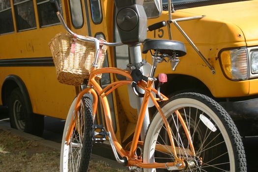 Orange bicycle poses in front of a yellow school bus in Los Angeles, California USA