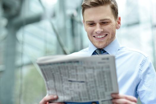 Image of a happy corporate male reading newspaper