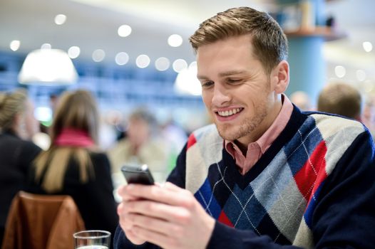 Young man smiling as he reads message on his phone